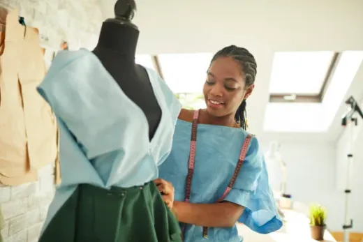 A garment maker fitting a dress on a mannequin