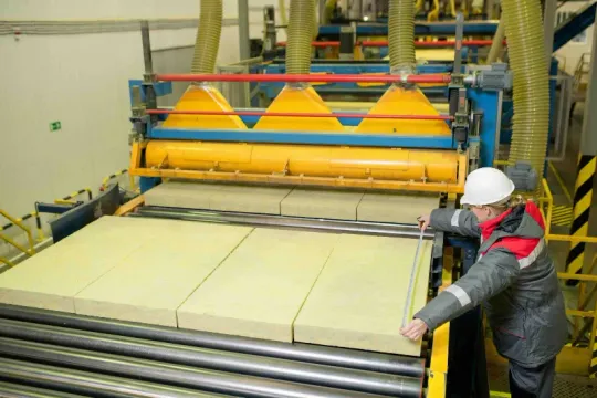 A production line operator measuring finished panels on a manufacturing line